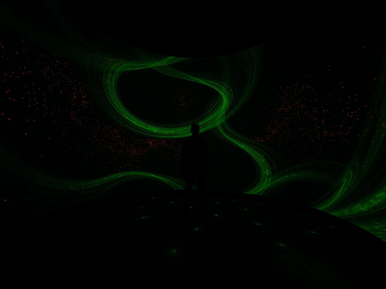 Visitor inside a projection-mapped immersive room with light patterns